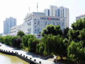 ein großes weißes Gebäude neben einem Fluss mit Bäumen in der Unterkunft Jinjiang Inn Select Nanjing Hanzhongmen in Nanjing