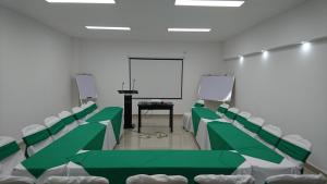una sala de conferencias con sillas verdes y blancas y una pantalla en Hotel Brandts Ejecutivo Los Robles, en Managua