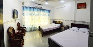 1 dormitorio con 2 camas, escritorio y sillas en Phuong Hue Hotel en Soc Trang