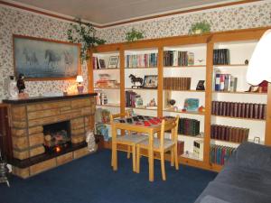 a living room with a fireplace and a table and book shelves at Gîte Les Acres Tranquilles B&B in Port-Daniel