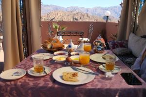 a table with plates of food and glasses of orange juice at Maison Tigmi Ozro in Tafraout