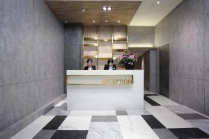 two people standing at a reception desk in a lobby at KEEBE Hotel in Keelung