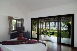 a bedroom with a bed and a patio with a table at Mali Resort Pattaya Beach Koh Lipe in Ko Lipe