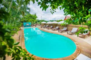 una piscina con tumbonas y sillas alrededor en Pongphen Guesthouse - SHA Plus Certified en Kanchanaburi