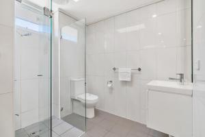 a bathroom with a toilet and a glass shower at Surf Beach Motel Coffs in Coffs Harbour +37 photos