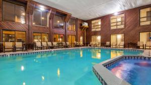 a large swimming pool in a building with tables and chairs at Best Western Plus Dockside Waterfront Inn in Mackinaw City