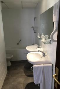 a white bathroom with two sinks and a toilet at Hôtel Du Nord in Longwy