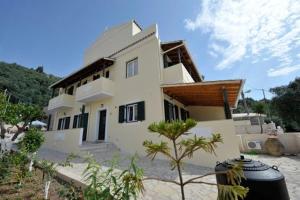 una casa bianca con un albero davanti di Votsalo Luxury Pool Apts a Kalámi