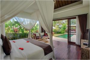 a bedroom with a bed and a swimming pool at Anusara Luxury Villas in Ubud +44 photos