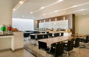 a restaurant with wooden tables and chairs and a counter at Amaris Hotel Darmo Surabaya in Surabaya