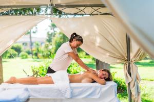 a woman laying on a bed while a woman is getting a massage at Club Hotel Marina Beach in Orosei