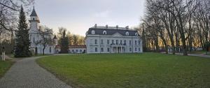 a large white house with a tower on a grass field at Dom Gościnny 8 km od Suntago, Deepspot in Radziejowice