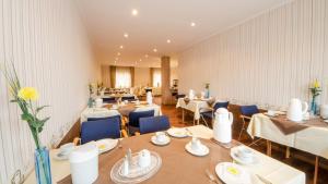 a restaurant with white tables and blue chairs at Hotel Alte Post in Lehrte