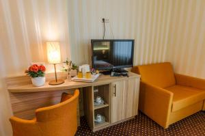 a hotel room with a tv and a couch and a chair at Hotel Alte Post in Lehrte