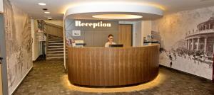 a woman standing at a reception desk in a lobby at City Hotel Ring in Budapest