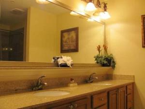 baño con 2 lavabos y espejo grande en Penthouse Blue Heron Condo en Orlando