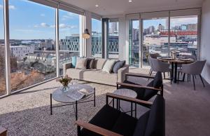 a living room with a couch and tables and windows at Swiss-Belsuites Victoria Park Auckland in Auckland