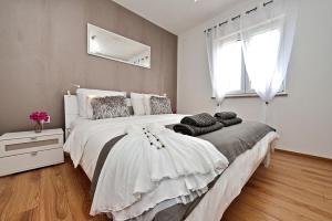 a bedroom with a large white bed with a window at Apartments Feel Good in Sukošan