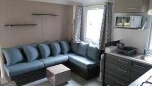 a living room with a blue couch and a sink at Les Dunes de Contis in Saint-Julien-en-Born