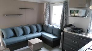 ein Wohnzimmer mit einem blauen Sofa und einem Waschbecken in der Unterkunft Les Dunes de Contis in Saint-Julien-en-Born