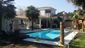 a house with a swimming pool in front of it at Villa Caraîbes in Gujan-Mestras