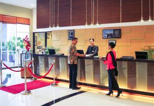 three people standing at a counter in a lobby at Mercure Surabaya in Surabaya