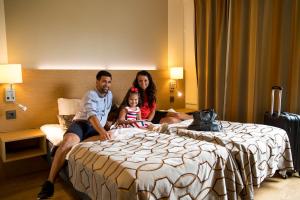 un uomo, una donna e un bambino seduti su un letto di Hotel Savoy a Mariehamn