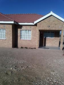 a brick house with a red roof at Fahms Self Catering in Letlhakawe