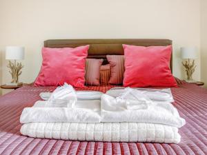 パリにあるWelkeys Apartment - La Fontaineのピンクの枕が付いたベッドの上にタオルを積み重ねる