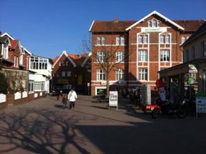 eine Gruppe von Menschen, die eine Straße mit Gebäuden entlanggehen in der Unterkunft FEWO Mövennest in Borkum + 8 Fotos