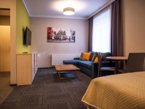 um quarto de hotel com um sofá e uma mesa em Aparthotel CENTRUM Gliwicka 18 em Bytom
