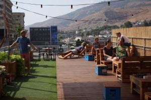 a group of people sitting on a patio with a mountain at Tiberias Hostel in Tiberias