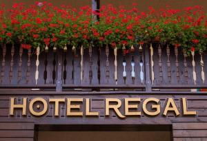 a sign for a hotel with red flowers on a fence at Hotel Regal in Sinaia
