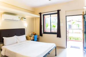 ein Schlafzimmer mit einem Bett und einem Fenster in der Unterkunft Lazy Frog Guest House in Cavelossim