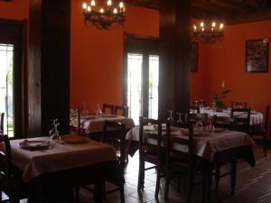 a dining room with tables and chairs with red walls at Hotel Rural El Caseron de Linarejos in Linarejos