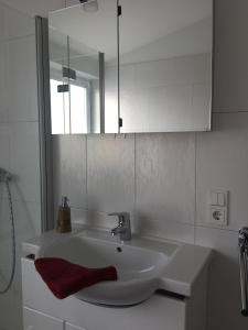 ボルクムにあるFewo Fabioのバスルーム(白い洗面台、赤いタオル付)
