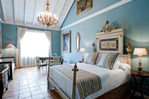 Hotel Hacienda de Abajo-Adults Only-Lujo في تازاكورتي: غرفة نوم بسرير بجدران زرقاء وثريا