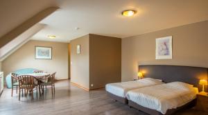 une chambre d'hôtel avec un lit, une table et des chaises dans l'établissement Hotel Lommel Broek, à Kerkhoven