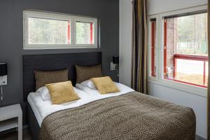1 dormitorio con 1 cama con 2 almohadas y 2 ventanas en Holiday Club Kuusamon Tropiikki Superior Apartments, en Kuusamo