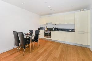 a kitchen with white cabinets and a table and chairs at Central Slough - 2 bedroom 1 bath in Slough