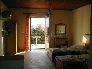 a bedroom with two beds and a door to a balcony at Erietta Studios in Svoronata