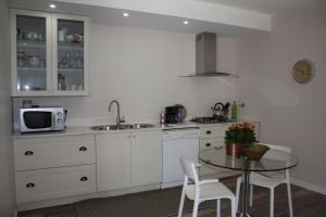 una cocina con armarios blancos y una mesa con sillas. en Areia Beach Guest House, en Vila do Conde