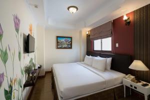 a hotel room with a white bed and a television at Asian Ruby Center Point Hotel & Spa in Ho Chi Minh City