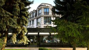 un edificio blanco con árboles delante de él en Boutique Hotel Central en Rivne