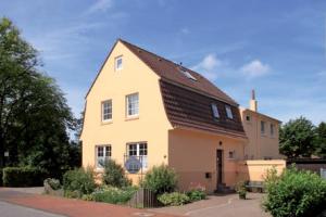 une grande maison jaune avec un toit brun dans l'établissement Gästehaus Alexandra, à Cuxhaven