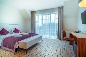 um quarto de hotel com uma cama, uma secretária e uma janela em Apartamenty M&M em Mikolajki