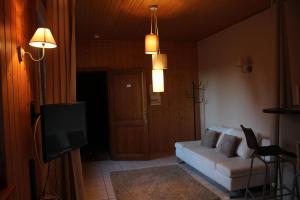 a living room with a white couch and a tv at Les gîtes de la Serva in Belmont