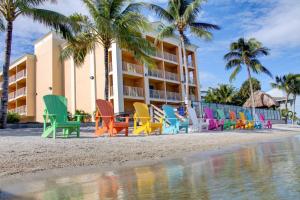 a row of colorful chairs on the beach in front of a hotel at Hutchinson Island Plaza Hotel & Suites in Fort Pierce