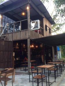 a restaurant with wooden tables and chairs and a sign at The Shadow House & Bar in Ko Phayam
