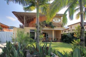 a house with palm trees in front of it at Pousada Villa Maritima in Juquei